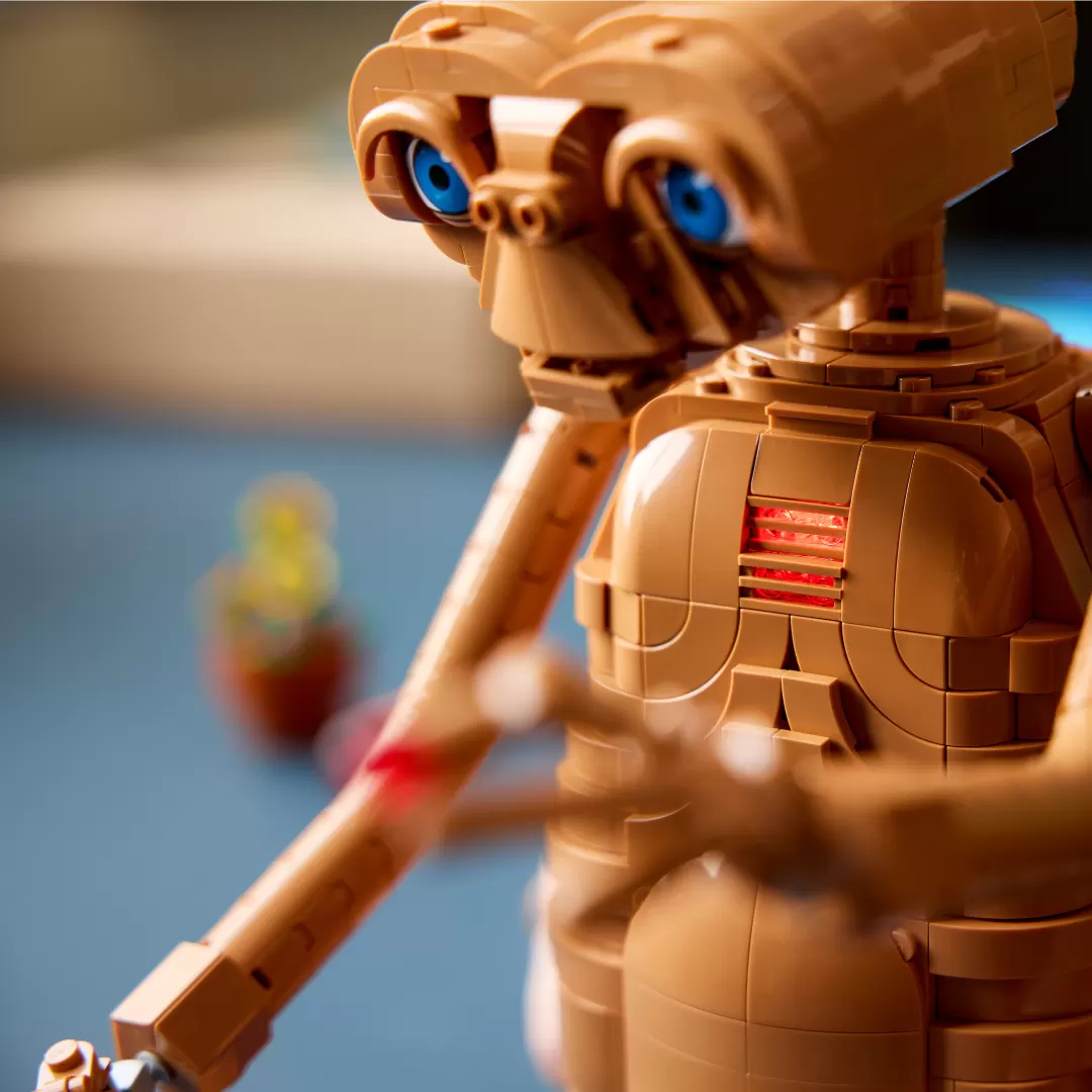 LEGO E.T. figure with glowing red heart chest piece and blue eyes against blurred background.
