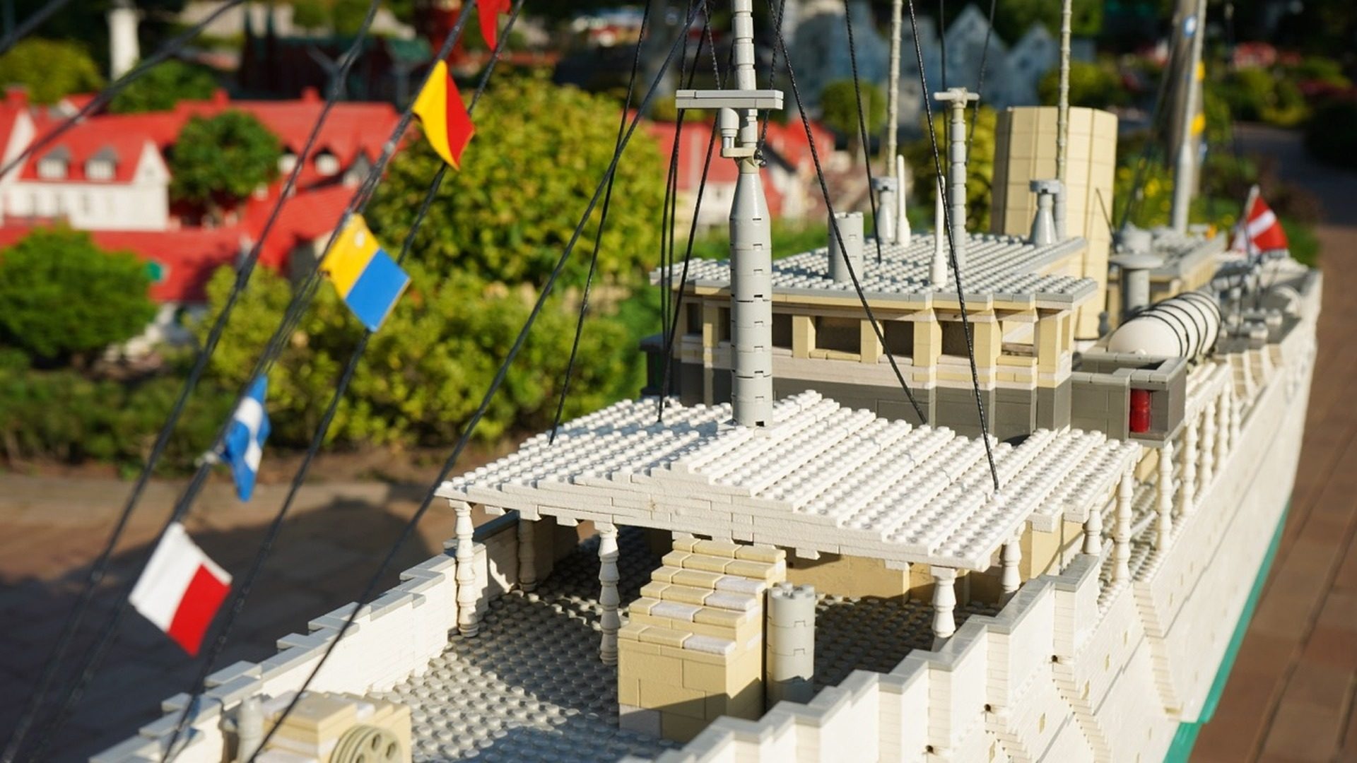 LEGO model of a castle with white brick walls, multiple towers, and flags including Poland and Romania, displayed at LEGOL…