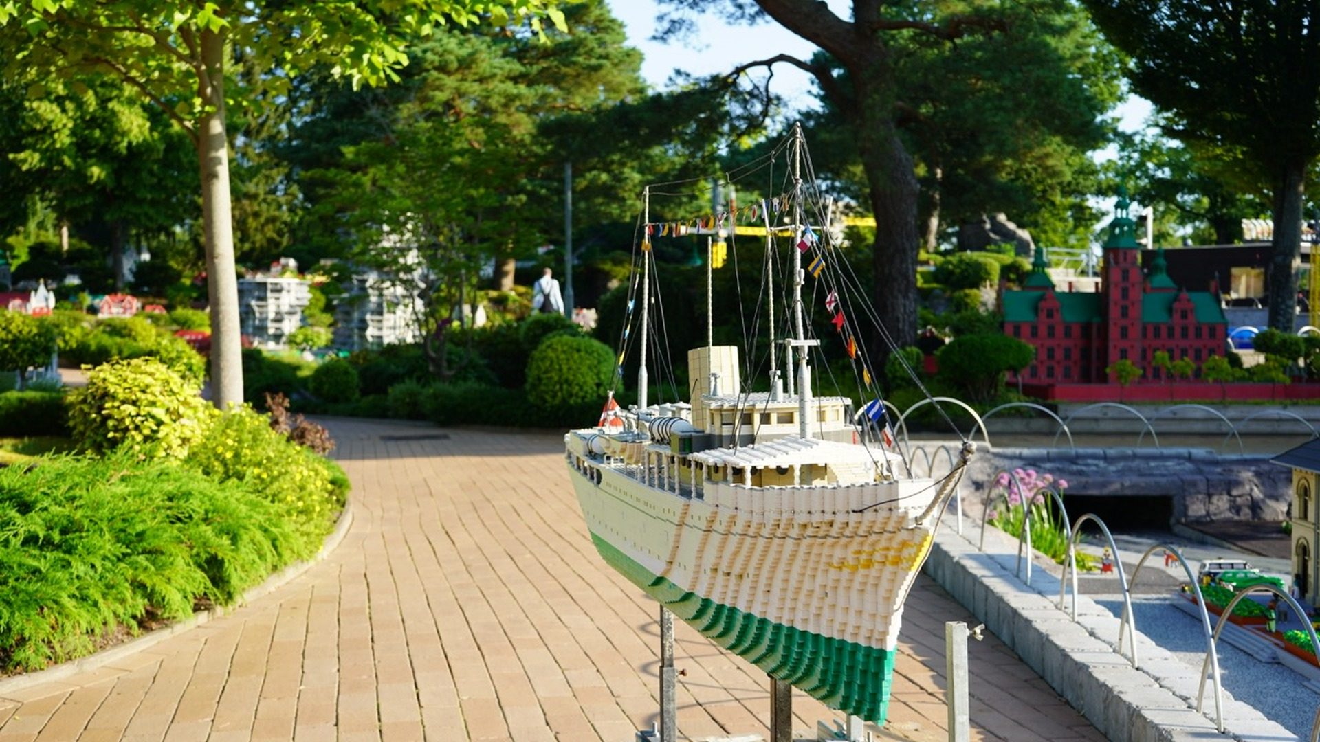 LEGO ship model docked at LEGOLAND park with green landscaping and castle structures in background.