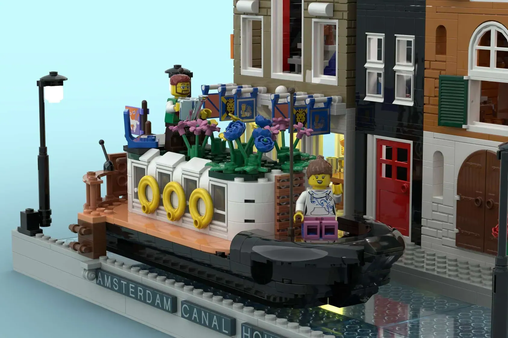 LEGO Amsterdam Canal set with decorated boat, canal houses, flowers, and minifigures on blue baseplate.