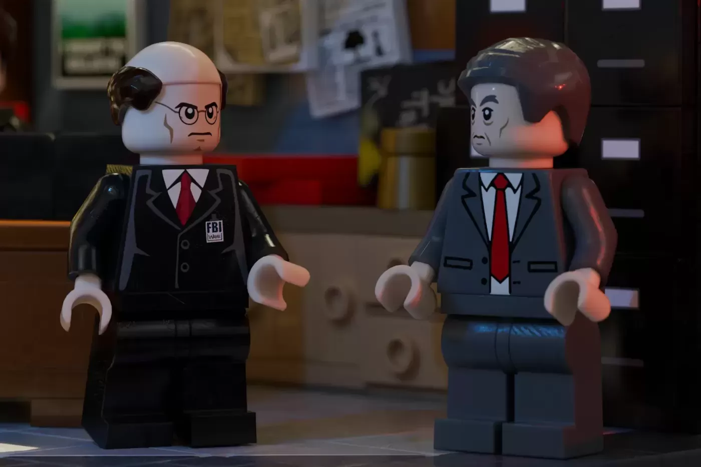 Two LEGO minifigures in FBI suits with red ties stand in an office setting, recreating X-Files characters.