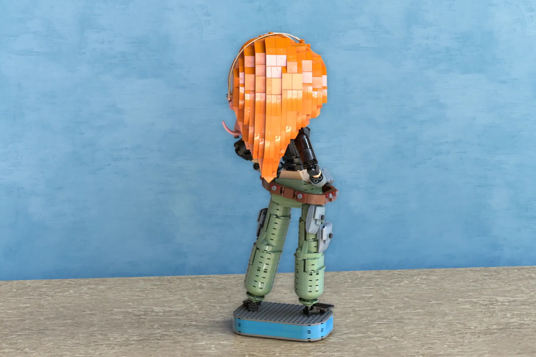 LEGO Ideas Kim Possible set with pixelated orange head and green body on blue baseplate against blue background.