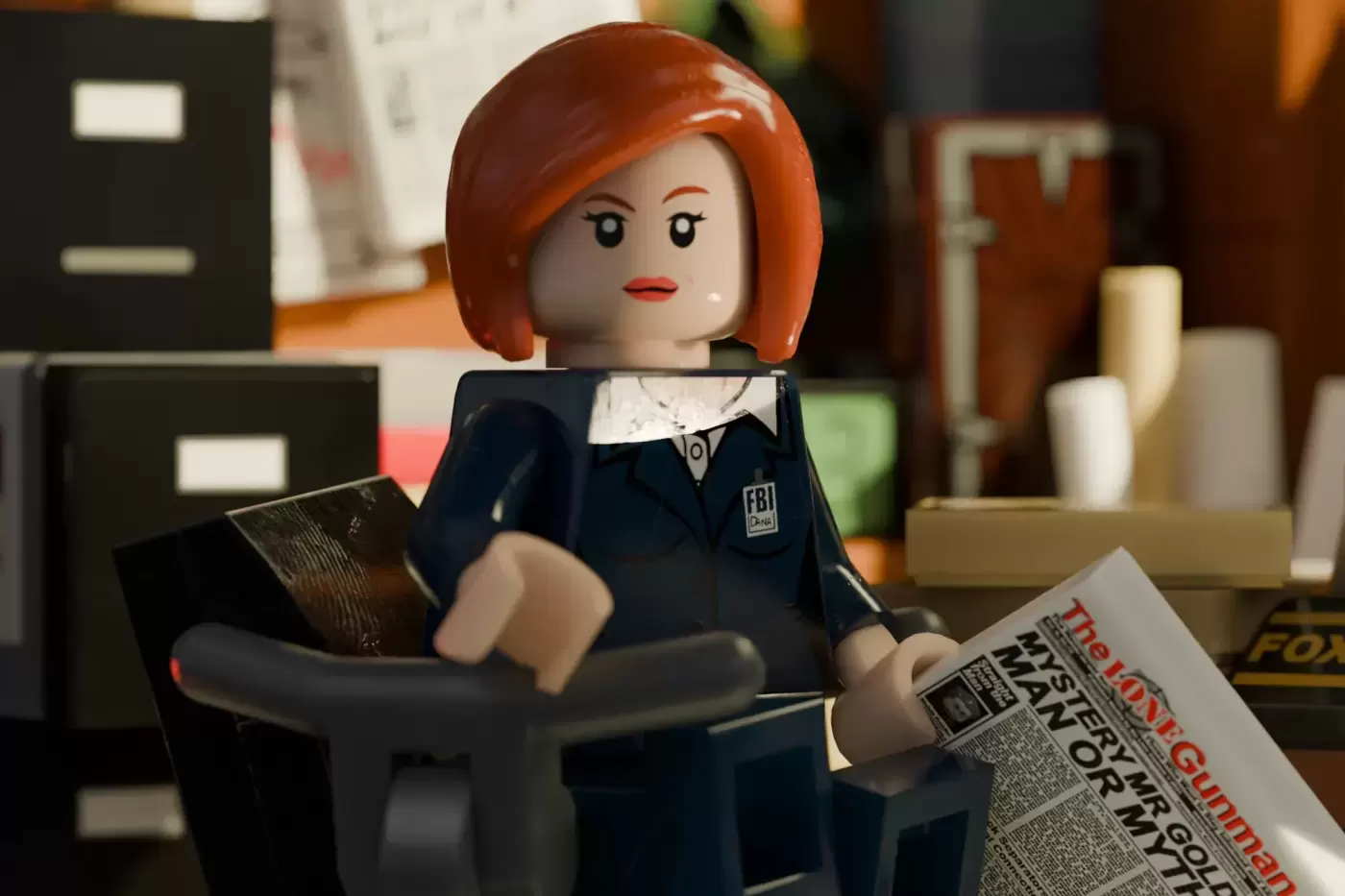 LEGO minifigure with orange hair in FBI suit holding newspaper in office setting with desk and filing cabinets.