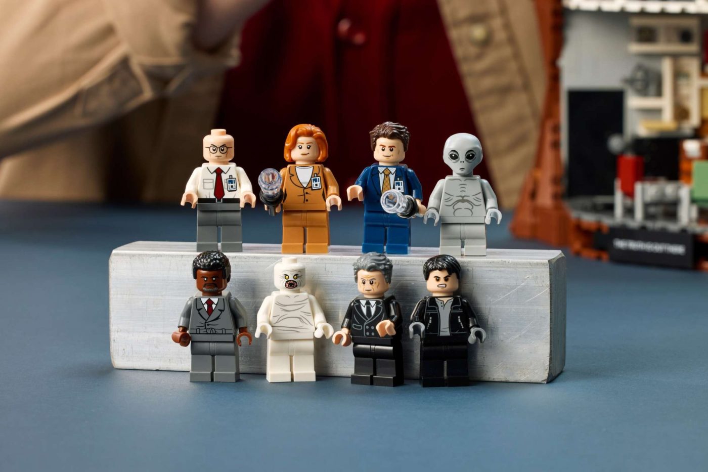 LEGO minifigures from The X-Files set arranged on a white podium, including agents, aliens, and characters in various outf…