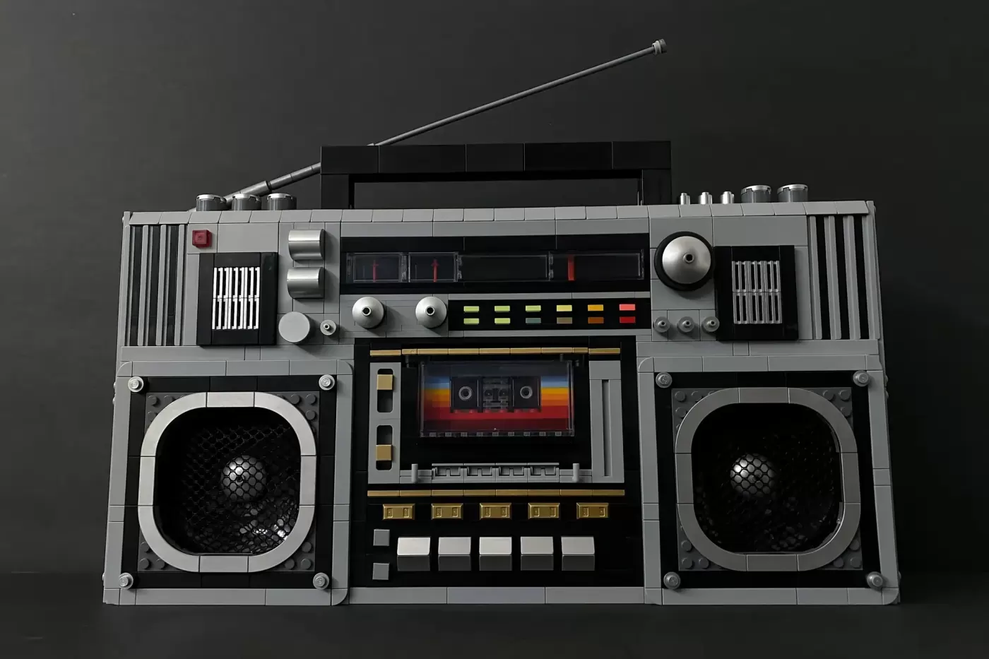LEGO boombox with dual cassette decks, central display, speakers, antenna, and detailed 1980s-style controls on dark backg…