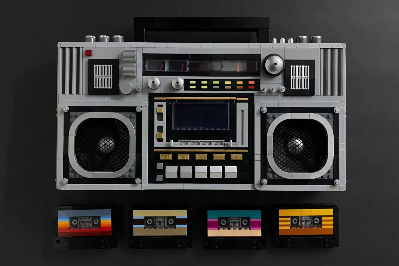 LEGO boombox with dual cassette decks, display screen, and colorful cassette tapes below, inspired by 1980s hip-hop culture.