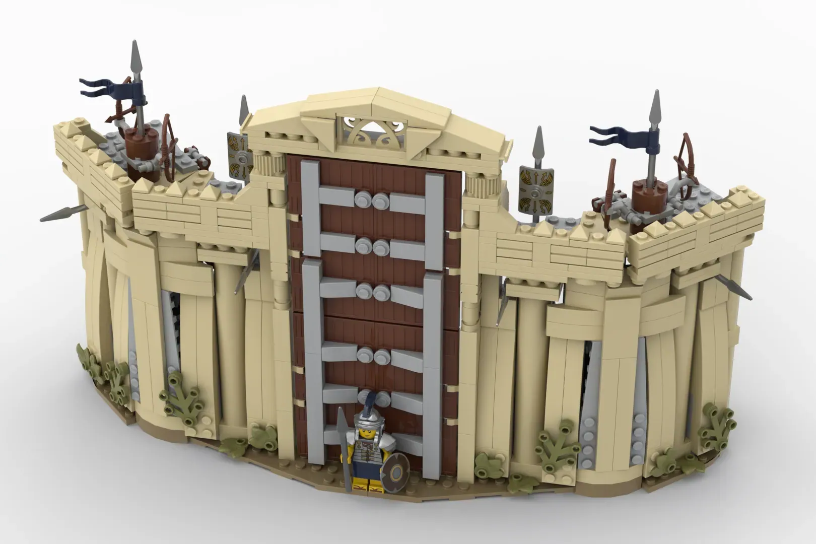 LEGO fort structure with tan walls, wooden gate doors, four corner towers with flags, and minifigure soldier at entrance.